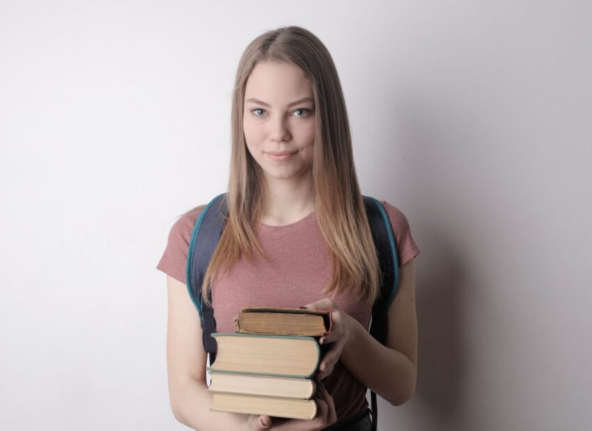 woman in red crew neck t shirt holding books